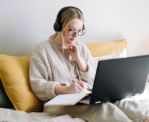 High school student with her headphones on and working with her laptop