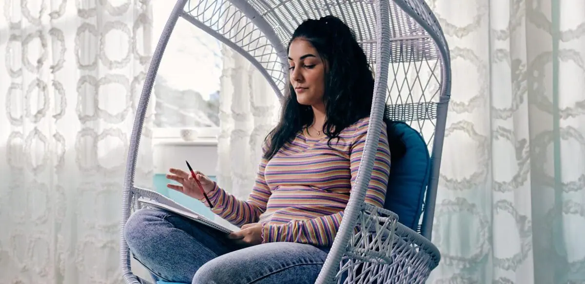 High school student taking notes at home wearing a stripped shirt